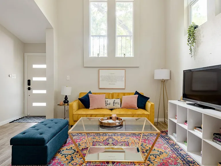 Living room, which has been updated to feature two light blue velvet chairs and another plush pink futon.