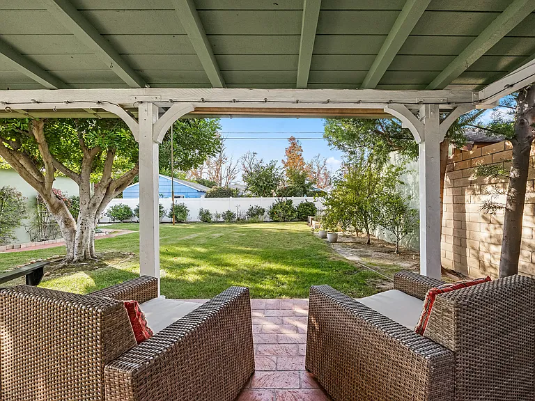 Spacious, fully fenced backyard with two distinct patio sections and seating in each.