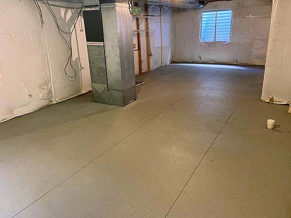 Large basement with painted floor and several big windows.