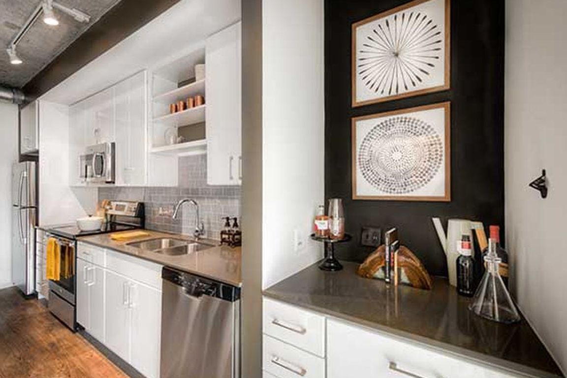 Kitchen with white cabinetry, quartz countertops, stainless steel appliances, tile backsplash and hard surface flooring