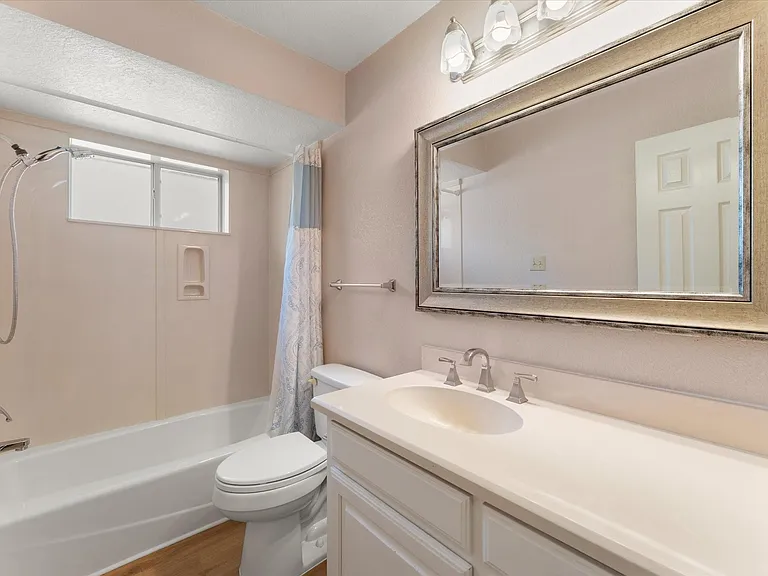 Bathroom featuring a single vanity with an integrated sink, polished chrome faucet, and a large framed mirror