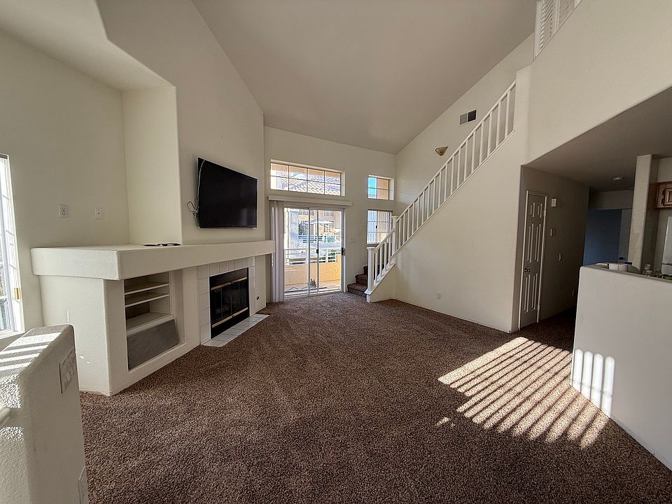 Living Room with fireplace and TV, patio has view of green belt, stair to loft.