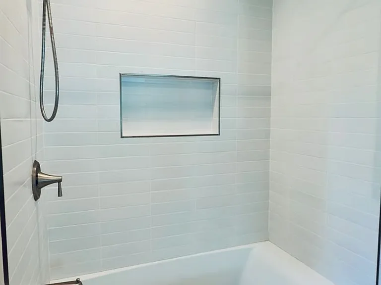Clean, modern bathroom with full bathtub and shower, perfect for relaxing after a long day.