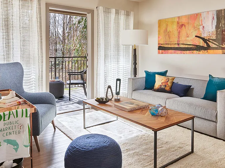 Apartment living room with wood-style flooring and patio or balcony in select homes.
