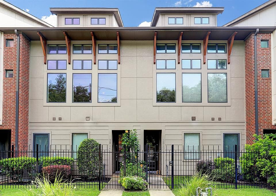 The home, on the left, has a well-maintained front yard and a wall of windows that allow lots of light to enter the property.
