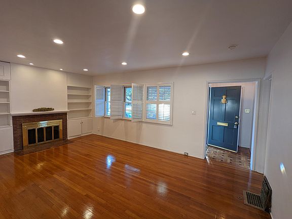 living room with hardwood floors, recess lights, fireplace, built in bookshelves, 3 windows looking in to the entry porch