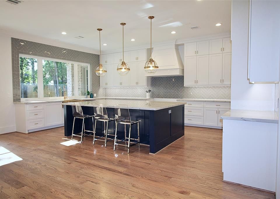 Natural quartzite counter tops are accented with glass herringbone tile work and custom built cabinetry. Brass pendant lighting illuminates the grand island with double sided storage.