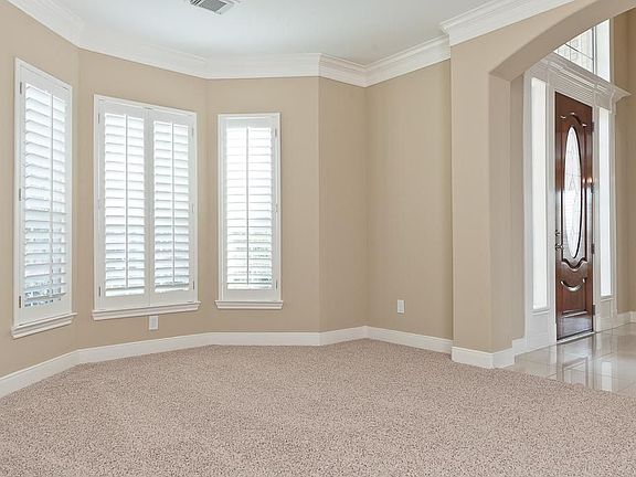 The living room has a decorative archway, recent frieze carpet, double crown moulding and plantation shutters.