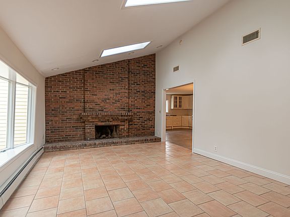 Spacious Living Room with bay window, skylights, vaulted ceiling and two-story brick fireplace.
