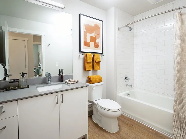 Bath with grey quartz countertops, white cabinetry, and hard surface flooring