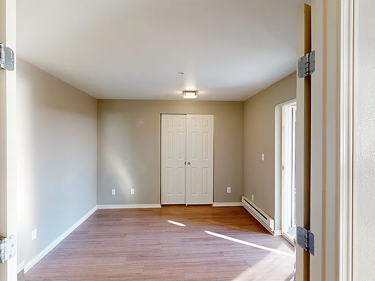 Spacious apartment bedroom with wood-style flooring.