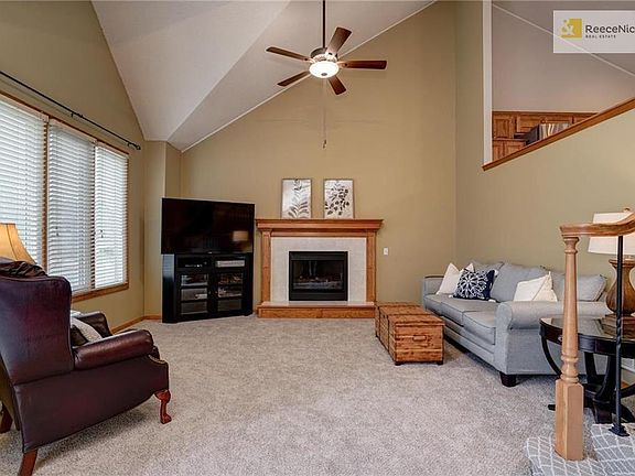 Large living room with gas fireplace, vaulted ceilings and new carpet.