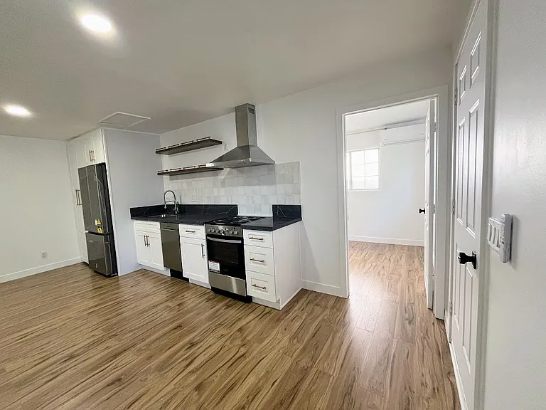 Kitchen. Main door on the right. Open door to bedroom ahead.
Washer and dryer are in the far left cabinet.