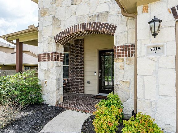 Brick and stone exterior along with mature trees and lush landscaping offers great curb appeal!