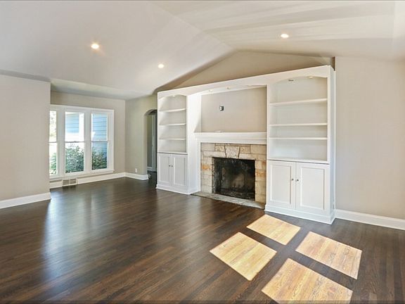 Vaulted ceiling with recessed lighting. Features large stone mantle with wood burning fireplace. Sym
