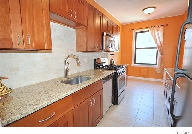 New Eat-in-Kitchen with granite counters, custom cherry cabinets, and stainless steel appliances including a dishwasher, microwave, rang and refrigerator.