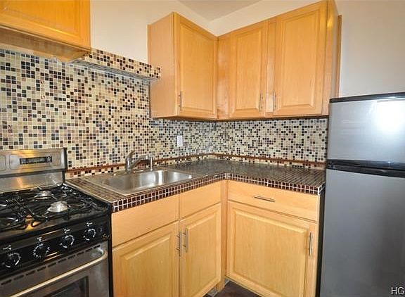 New kitchen with stainless steel appliances and decorative glass tile back splash.