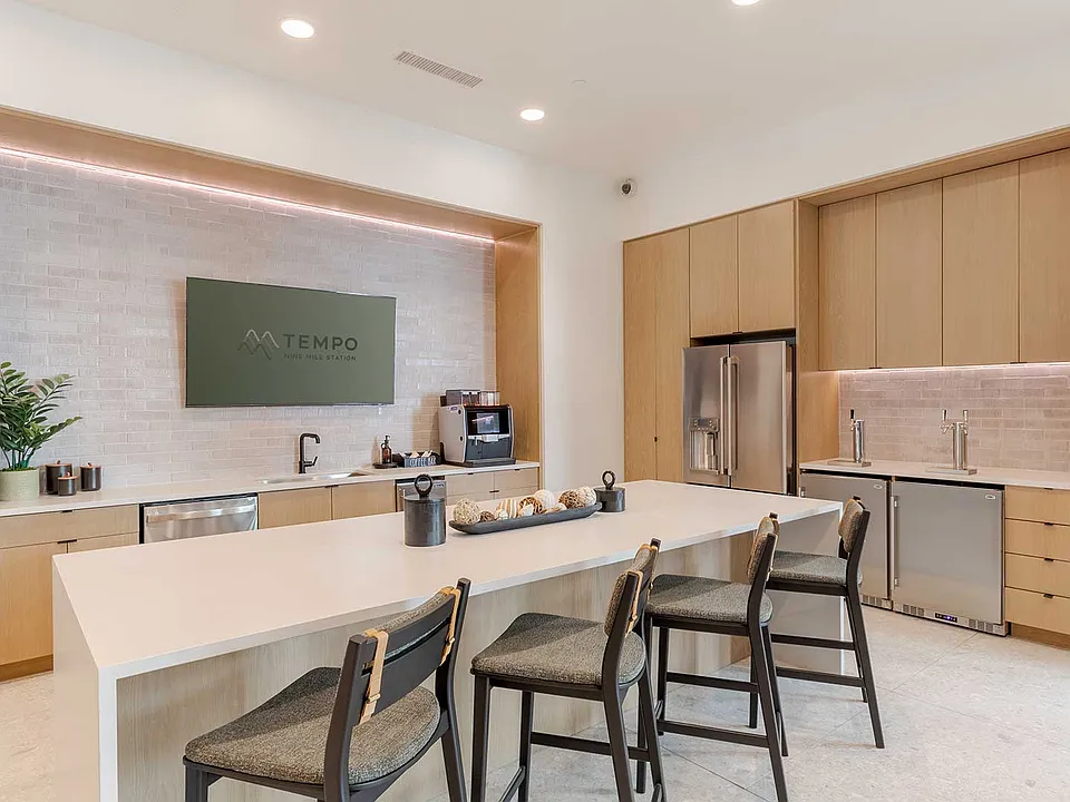 Entertain, recharge, or connect with neighbors in a modern community kitchen featuring expansive seating, coffee service, and contemporary finishes.