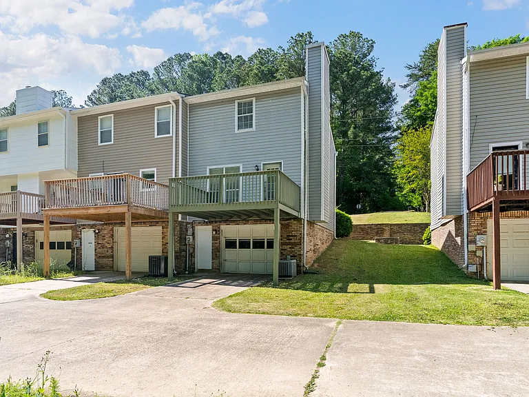 Rear view of the home showcasing the garage/basement, private parking pad, and elevated back deck