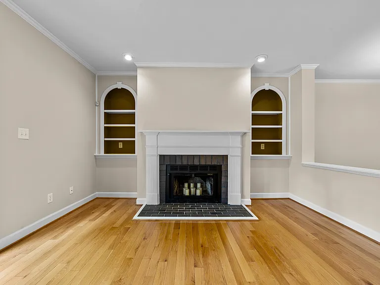 Fireplace focal wall framed by arched built-in shelving and recessed lighting.