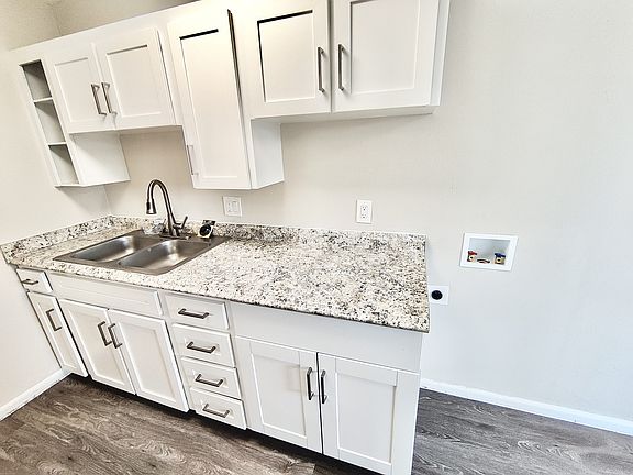 Modern kitchen with sleek white cabinets, elegant granite countertops, and a double stainless steel sink.