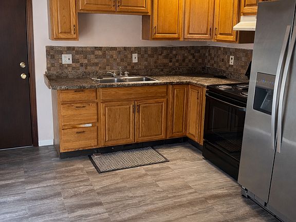 Kitchen
Functional kitchen with solid wood cabinetry, tile backsplash, laminate countertops, stainless refrigerator, and electric range. Durable flooring and efficient layout maximize storage and workspace for everyday cooking.