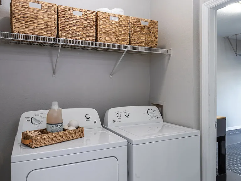 A dedicated laundry space featuring full-sized appliances and built-in shelving for added storage and efficiency.