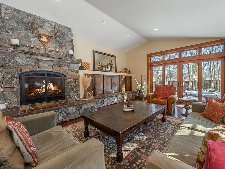Living room with remote control gas fireplace, TV w/ surround sound, a piano and sliding doors to both patios
