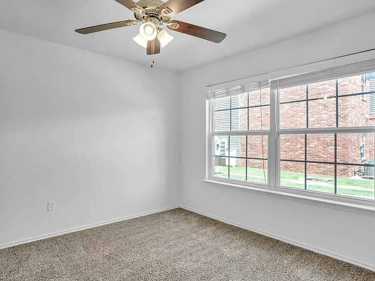 Bright and cozy bedroom with plush carpeting, ceiling fan, and large window offering abundant natural light. Bright and cozy bedroom with plush carpeting, ceiling fan, and large window offering abundant natural light.