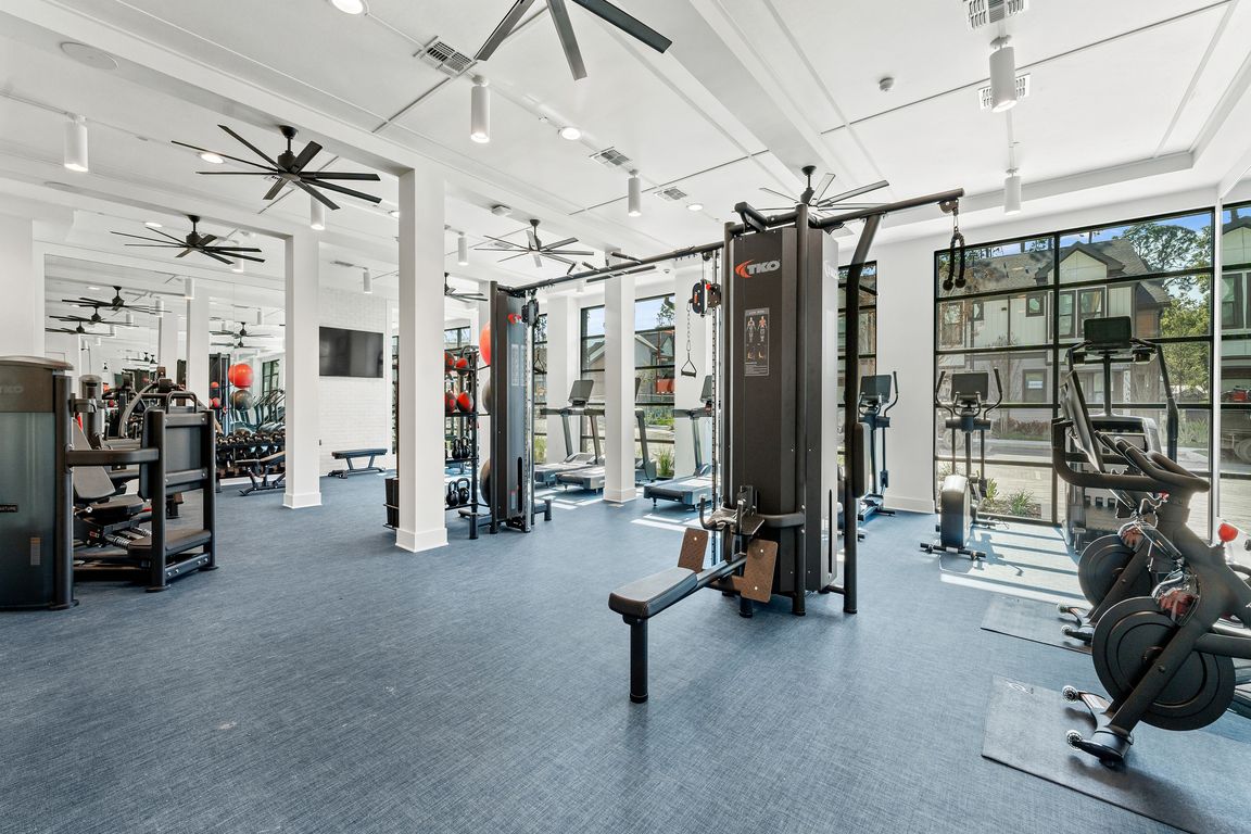 State-of-the-art fitness center featuring modern exercise equipment, high ceilings, and abundant natural light for an invigorating workout experience.