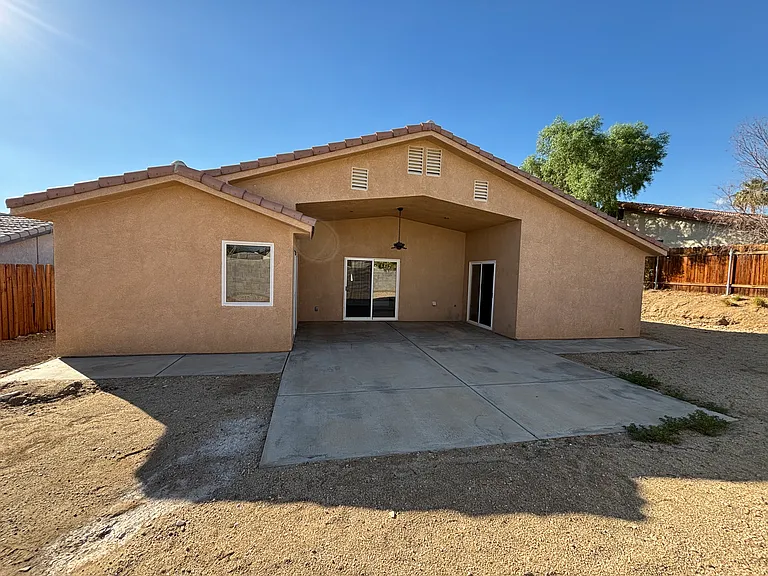 Private fenced backyard with a covered patio and large concrete area for outdoor seating and dining.