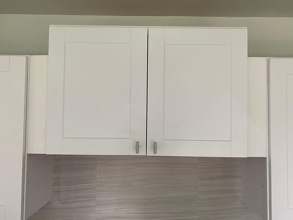 New kitchen cabinets in a white-satin shaker with modern knobs.