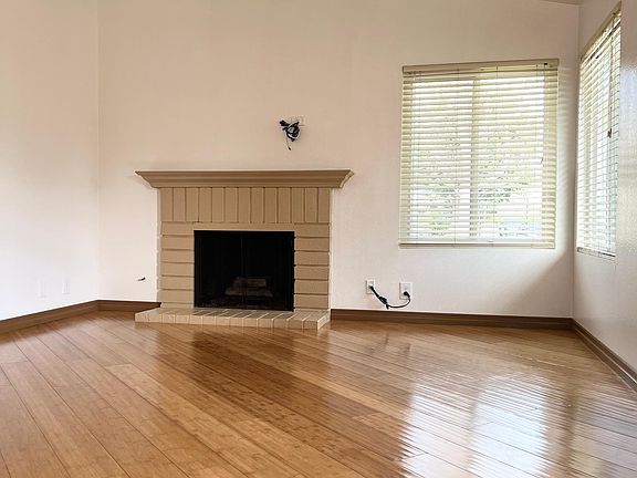 Living room with gas fireplace, bright corner windows, high ceiling and beautiful, hardwood floors throughout
