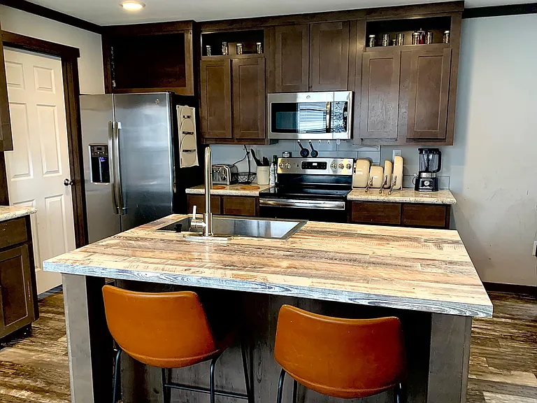 Kitchen with a large island, ample cabinet storage, and stainless steel appliances including fridge, range, and microwave.
