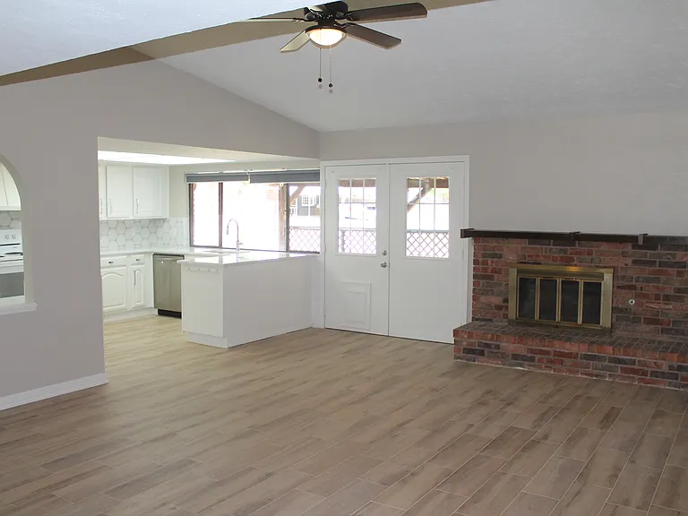 High ceiling open concept family living space with cozy fireplace flowing to the kitchen