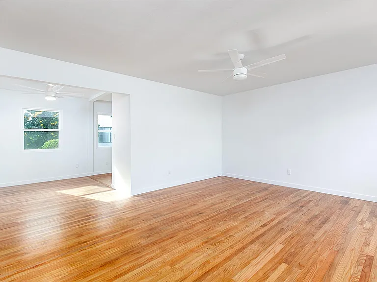 Living room. The dining room is to the left side of the photo and the kitchen window and door with half window are seen behind the living room wall.