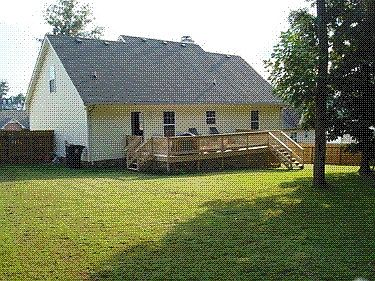 Fenced in backyard with large deck