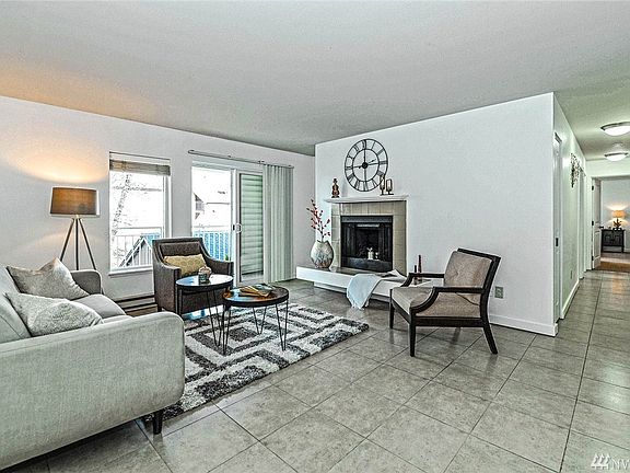 Inviting light filled living room with wood fireplace, balcony and tile floors.