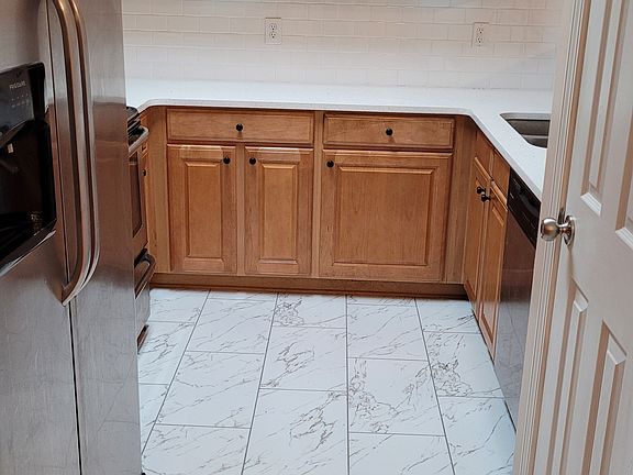 Kitchen with new quartz countertop, subway tile backsplash, marble look tile, and pull-down faucet.
