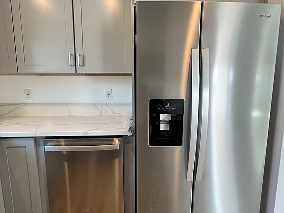 View of new dishwasher and refrigerator with water and ice dispenser.