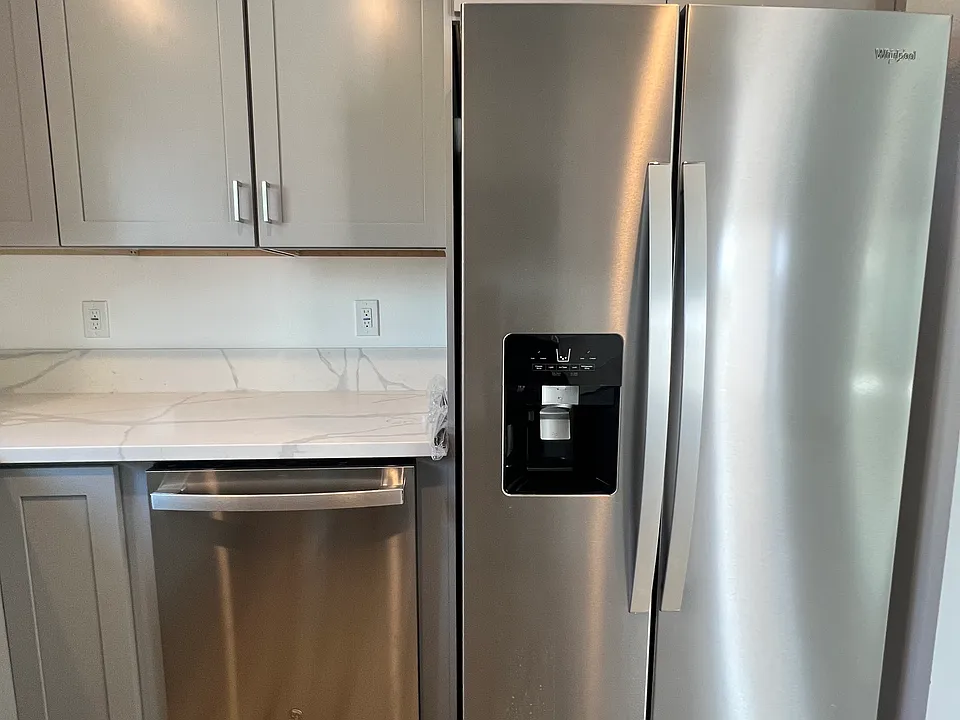 View of new dishwasher and refrigerator with water and ice dispenser.