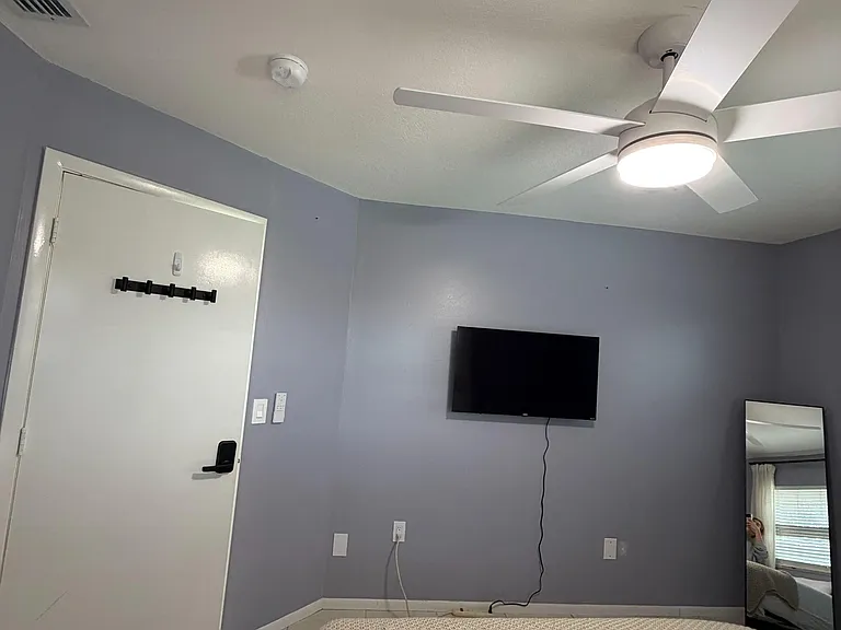 Bedroom with tile flooring, ceiling fan with light, and a wall-mounted TV plus space for additional storage.