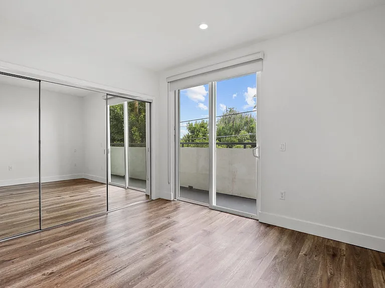 Bedroom with Mirrored Closet, Balcony, and Vinyl Flooring