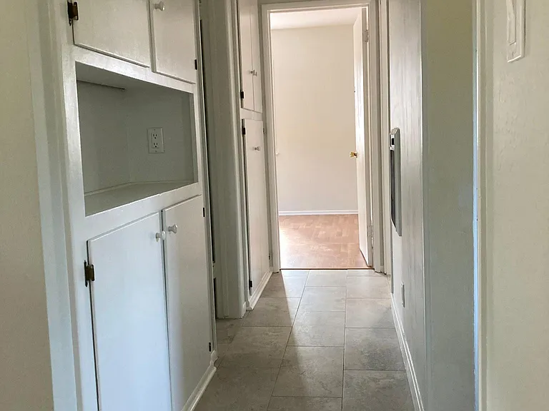 Hallway with ceiling to floor cabinets and wall heater.