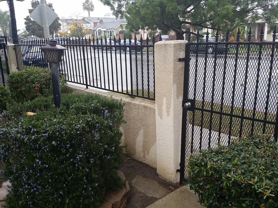 Close up of front Gate leading to walkway of flowers and greenery.