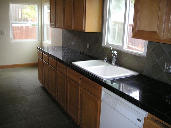 Interior kitchen features granite tile, slate flooring, oak cabinetry.