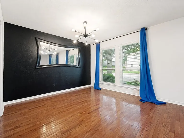 Room featuring wood-finish flooring, a black accent wall, and a contemporary sputnik-style chandelier