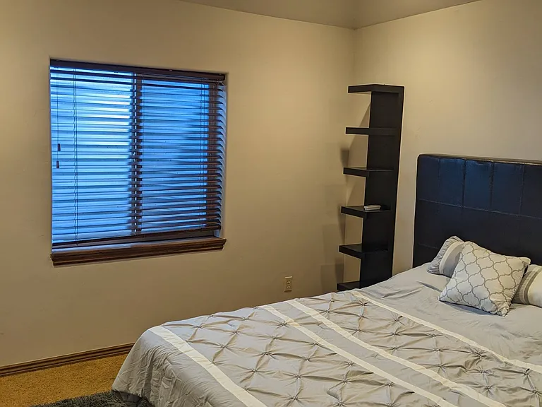 Bedroom (furniture not included) with window leading to side yard. Fan complements central air conditioning