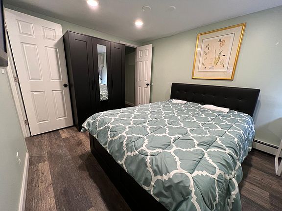 Second Bedroom. Ensuite bathroom, completely furnished with queen storage bed with four drawers, armoire with shelves and hanger, desk and mod red office chair. On right wall just out of view is flat screen TV on the wall with wifi and 200 cable channels.