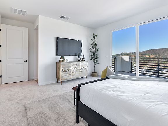 A modern and spacious bedroom with a large window overlooking a scenic outdoor landscape, featuring